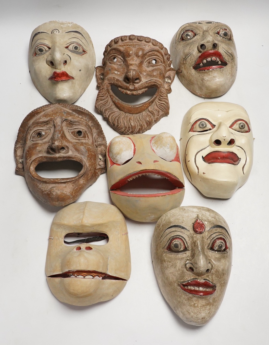 Two pottery face masks, and three pairs of carved and painted masks, largest mask 21cm high